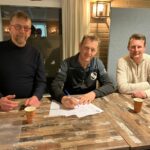 Trainer Duteweert bij zijn contractverlenging, geflankeerd door links voorzitter Johan Roetert en rechts penningmeester Barry Beldman.